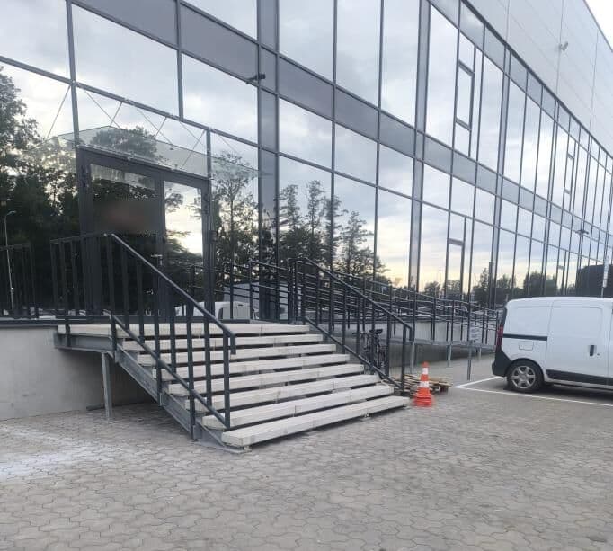 Ārējās ieejas kāpnes ar tērauda margām pie stikla fasādes