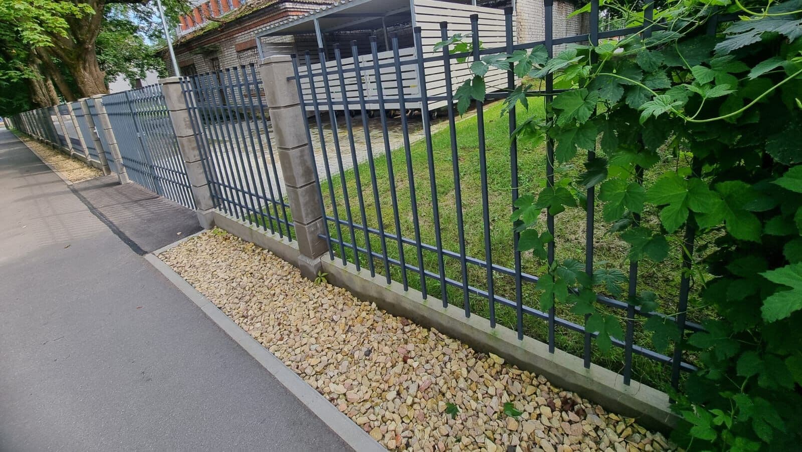 Tērauda žogs ar stabiem gar ielu